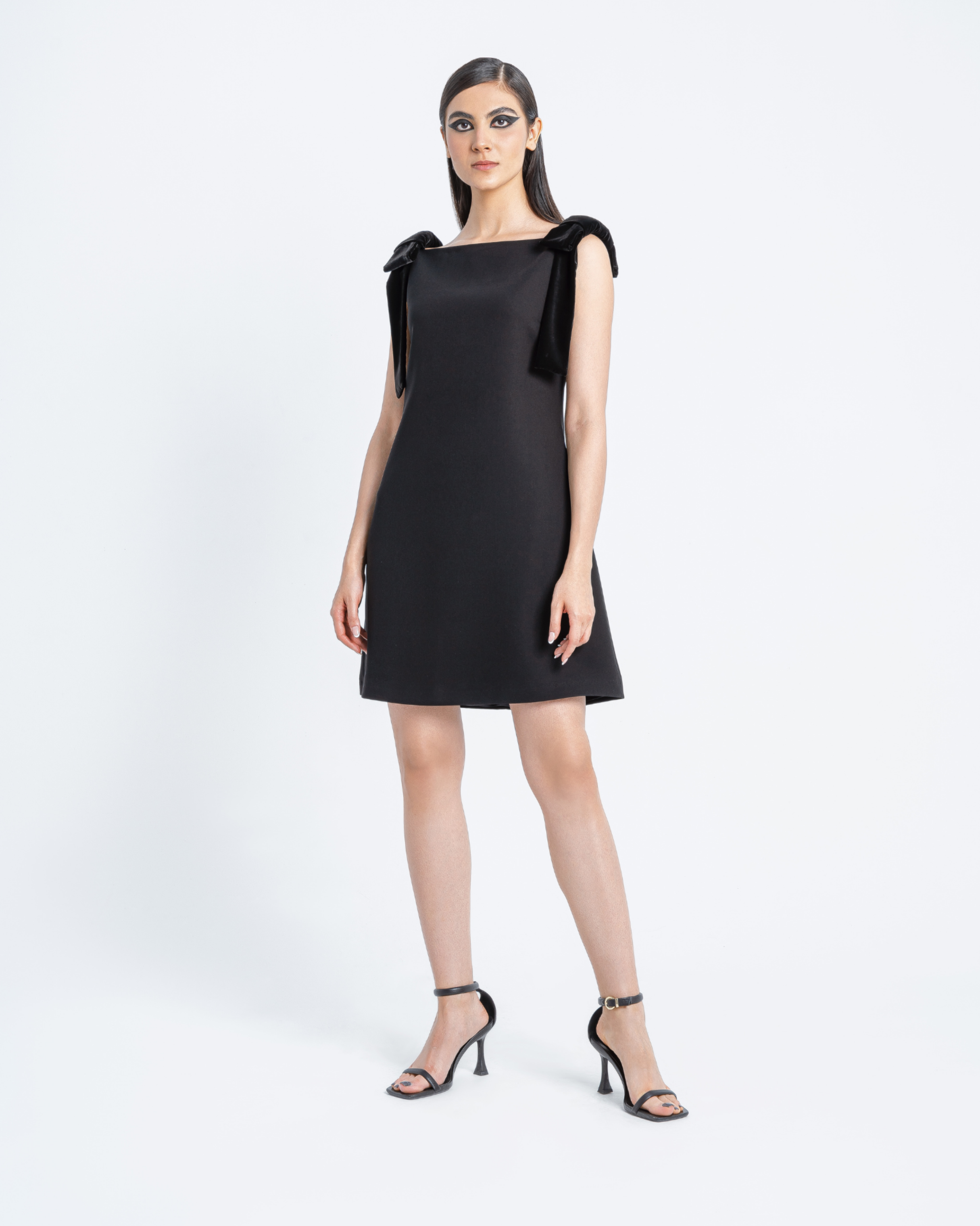 Model wearing Hüna Fara Dress — black crepe mini dress with velvet shoulder bows, limited edition design
