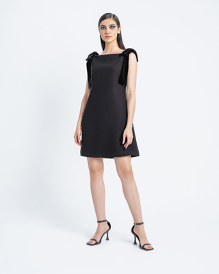 Model wearing Hüna Fara Dress — black crepe mini dress with velvet shoulder bows, limited edition design