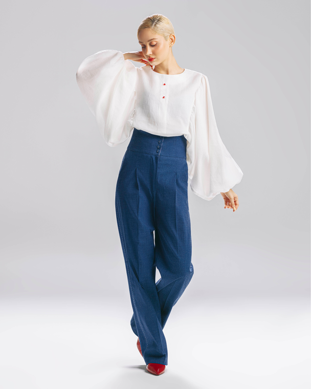 Model wearing Hüna Nina Blouse — premium white linen blouse with puff sleeves and decorative red buttons, limited edition design