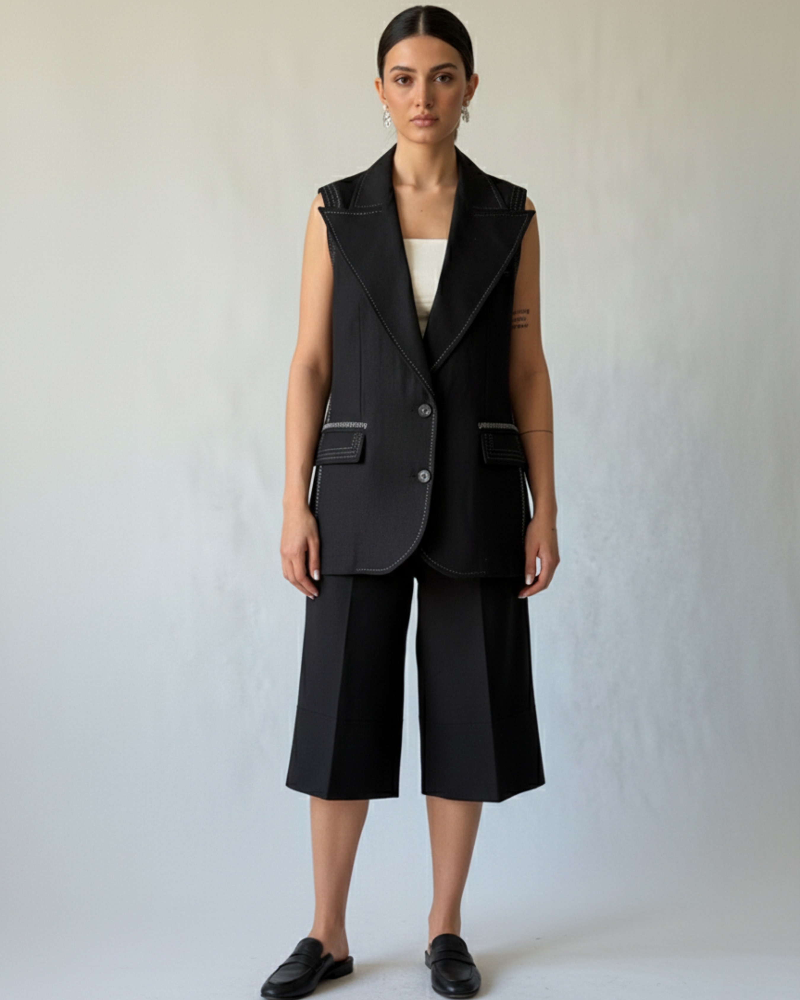 Model wearing Hüna Andia Waistcoat — sleeveless linen blazer with decorative contrast stitching, limited edition design